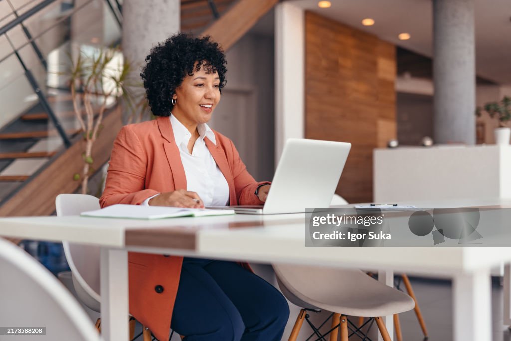 Lächelnde Geschäftsfrau, die im Büro am Laptop arbeitet