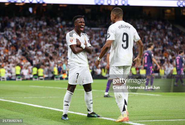 Vinicius Junior of Real Madrid celebrates with teammate Kylian Mbappe after scoring his team's third goal during the LaLiga match between Real Madrid...