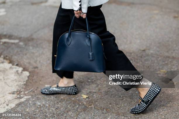Guest wears white jacket, black skirt, Alaia shoes, navy bag outside Ferragamo during the Milan Fashion Week Menswear Spring/Summer 2025 on September...