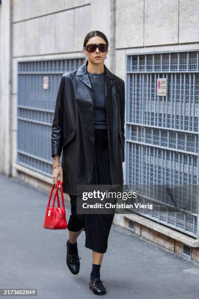 Guest wears black skirt, blazer, red bag outside Bally during the Milan Fashion Week Menswear Spring/Summer 2025 on September 21, 2024 in Milan,...