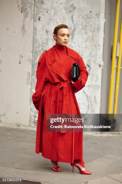 Guest wears red turtle neck top, long red coat, black bag and red high heels outside Ferragamo show during the Milan Fashion Week Spring/Summer 2025...