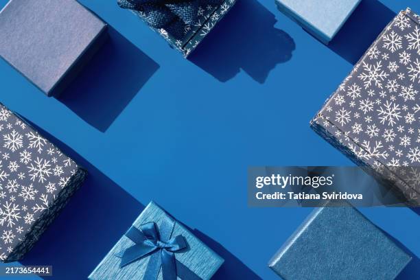 several blue gift boxes on blue background. snowflakes pattern - dark blue table stock pictures, royalty-free photos & images