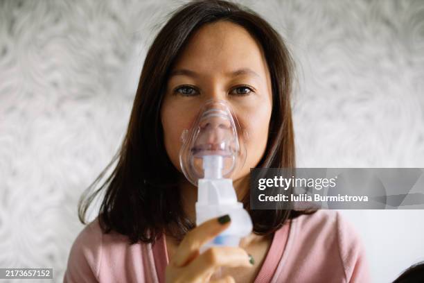 attractive lady uses nebulizer as part of self-care routine during challenging season of respiratory illnesses - nebulizer stock pictures, royalty-free photos & images