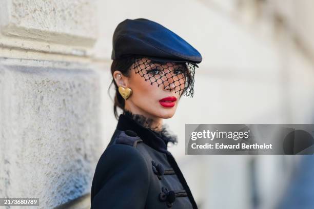 Heart Evangelista wears black hat with black sheer mesh lace veil Dolce & Gabbana hat, gold heart shaped earrings, black military cropped Dolce &...