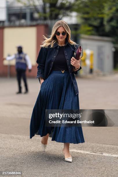 Guest wears black sunglasses, navy blue shirt, navy blue denim jean unbuttoned long sleeve shirt, navy blue pleated midi skirt, dark red leather...