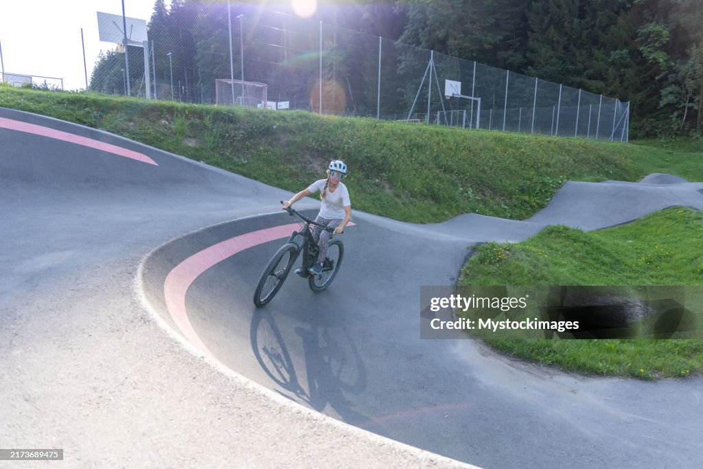 Woman Riding Bike on Pump Track Surrounded by Greenery