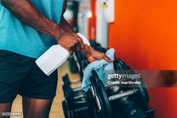 sportsman disinfecting sports equipment in the gym - fitnessapparatuur stockfoto's en -beelden