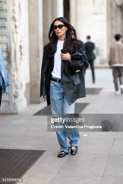 Giorgia Tordini wears black shiny leather ballerinas, silver hoop earrings, black sunglasses, a black belt, a black oversized leather jacket, a white...