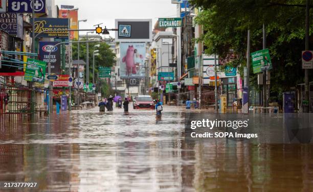 People seen walking through a heavily flooded street at the Night Bazaar area of Chiang Mai. Continuous rainfall has caused the Ping River to...