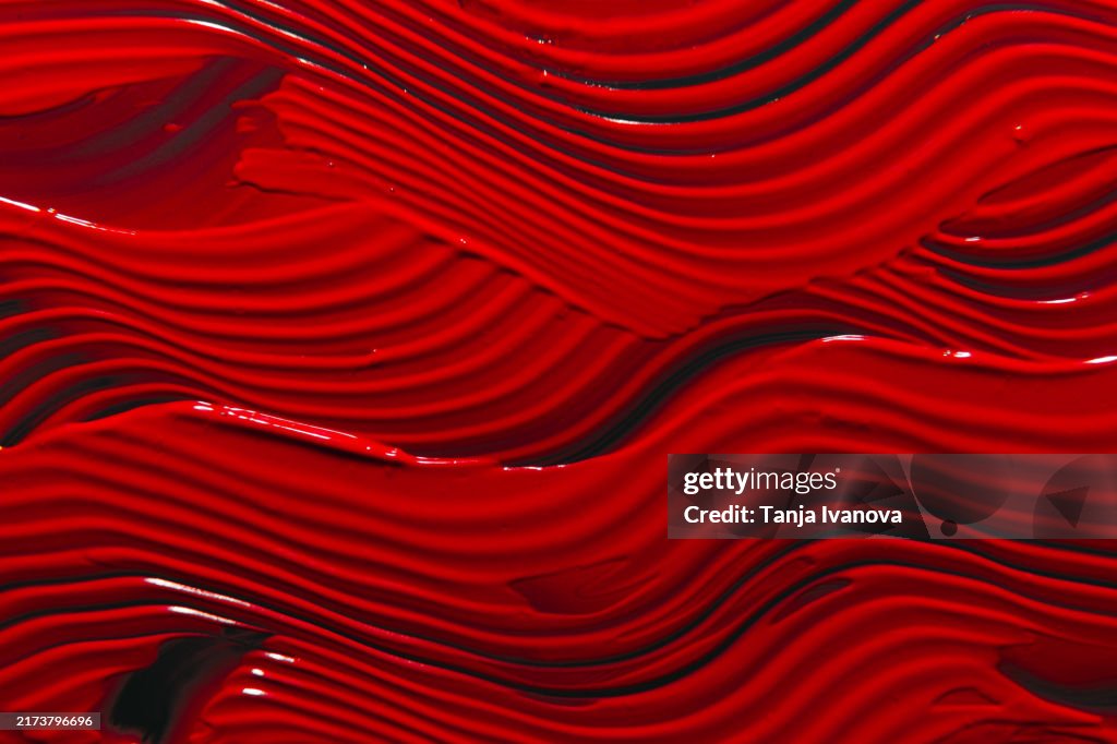 Red lipstick background. Beauty cosmetic texture. Makeup and skin care products. Textured red paint brush stroke on black background.