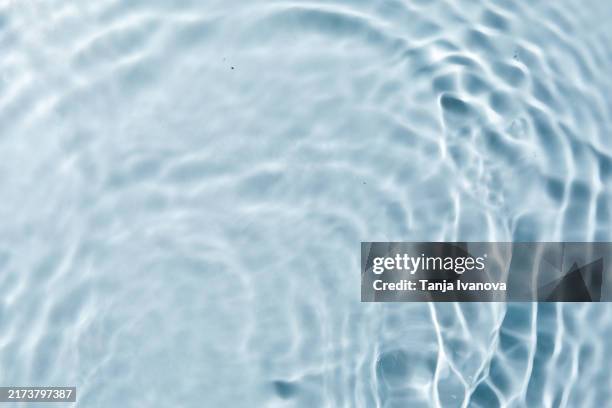 light blue transparent clear water surface texture with ripples, waves in sunlight and light reflections - wateroppervlak stockfoto's en -beelden