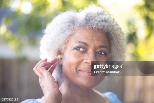 a beautiful senior black woman with a hearing aid - hearing loss stock pictures, royalty-free photos & images