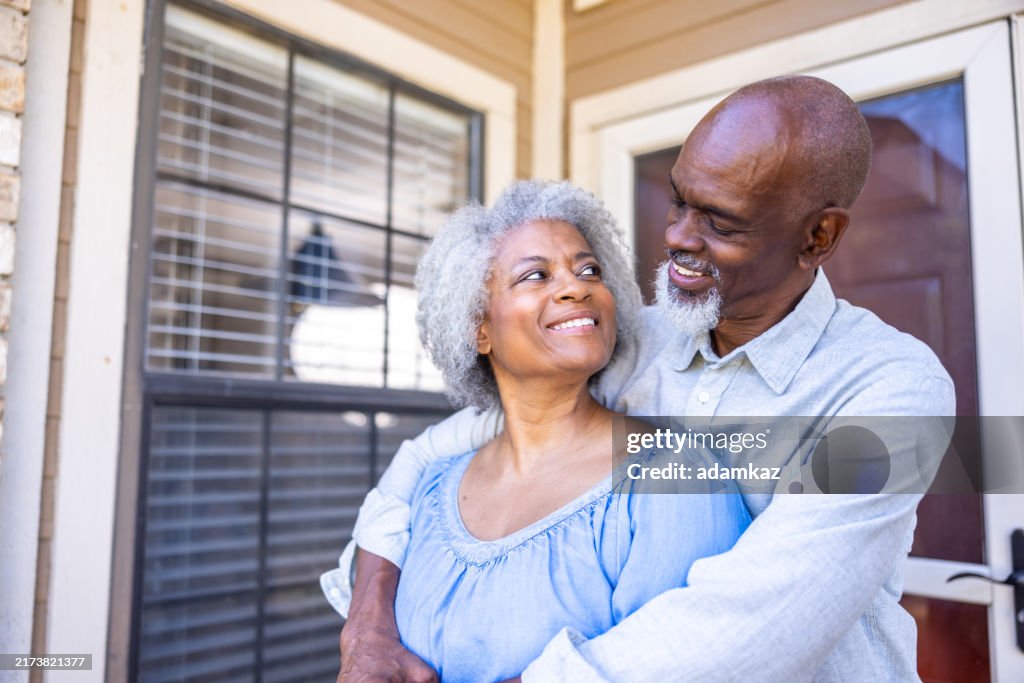Senior black married couple homeowners in front of their home