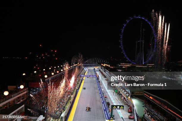 Race winner Lando Norris of Great Britain driving the McLaren MCL38 Mercedes takes the chequered flag as fireworks go off in the grandstands during...