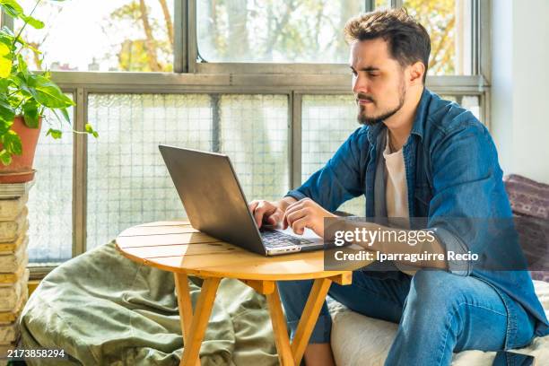 hispanic man using laptop in a home office - latin america stock pictures, royalty-free photos & images