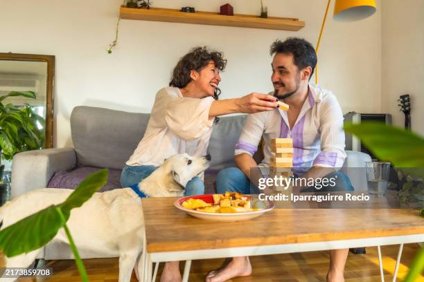 latin couple playing jenga block removal game sitting on the sofa - block removal game stock pictures, royalty-free photos & images