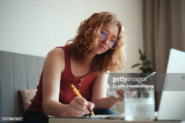 home finances. young woman calculating spendings looking at bills making notes using calculator. monthly expenses - savings stock pictures, royalty-free photos & images