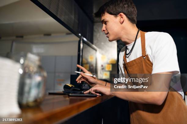 caucasian teenage boy working at the fast food restaurant - ober stockfoto's en -beelden