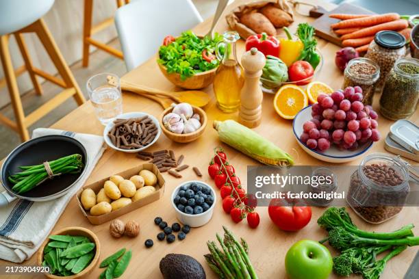 küchentisch voller frischem gemüse, obst und bohnen. konzept für gesunde ernährung - pflanzliche ernährung stock-fotos und bilder