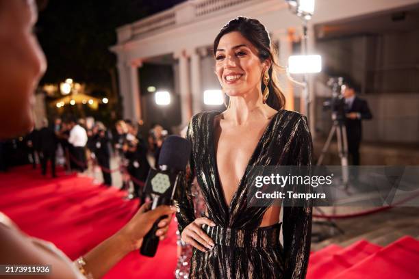 una animada entrevista en la alfombra roja se desarrolla mientras el reportero de televisión pregunta sobre el próximo estreno. - entrevista acontecimiento fotografías e imágenes de stock