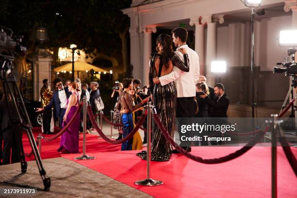 rear view shows male and female actors standing and observing the red carpet event. - evento com traje de cerimónia imagens e fotografias de stock