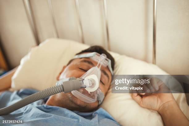 man sleeping with cpap machine on for sleep apnea - sleep apnea stock pictures, royalty-free photos & images