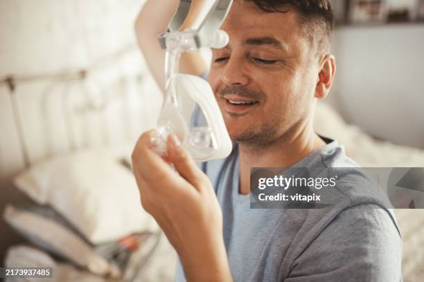 mann trägt cpap-gerät für schlafapnoe - schlafapnoe stock-fotos und bilder