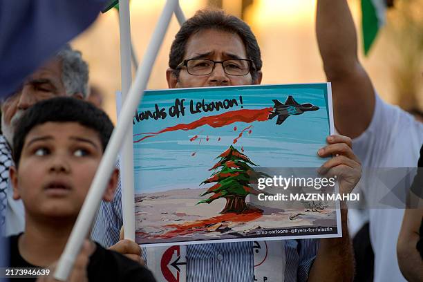Protesters hold placards and chant slogans during a rally in solidarity with the people of Gaza and Lebanon in the Bahraini capital Manama on...