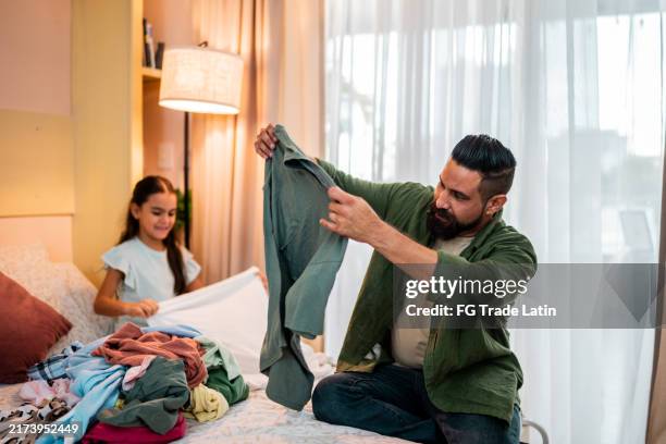 father organizing clothes at home - modern manhood stock pictures, royalty-free photos & images