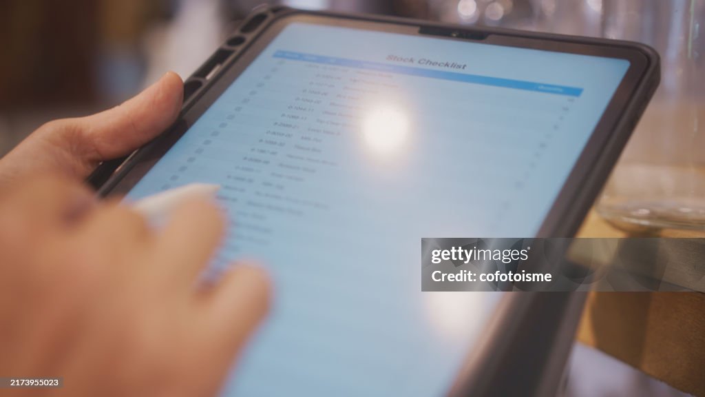 Close-up of a hand using a digital tablet to check the inventory in his home and garden decoration store.
