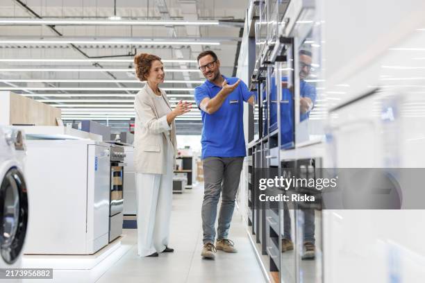 el cliente y el vendedor hablan sobre los electrodomésticos en la tienda moderna - electrodoméstico fotografías e imágenes de stock
