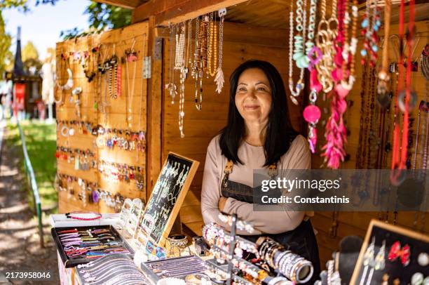 mature woman behind the jewelry stall - marktkoopman stockfoto's en -beelden