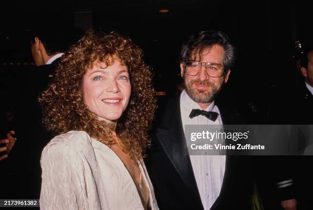 American actress and singer Amy Irving, wearing a white outfit with a choker-style necklace, and her husband, American film director Steven Spielberg...