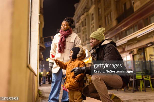 family enjoying nighttime window shopping - urban exploration stock pictures, royalty-free photos & images