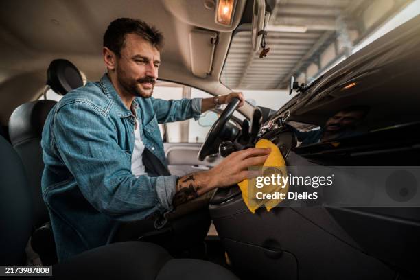young man wiping his car interior. - clean car interior stock pictures, royalty-free photos & images
