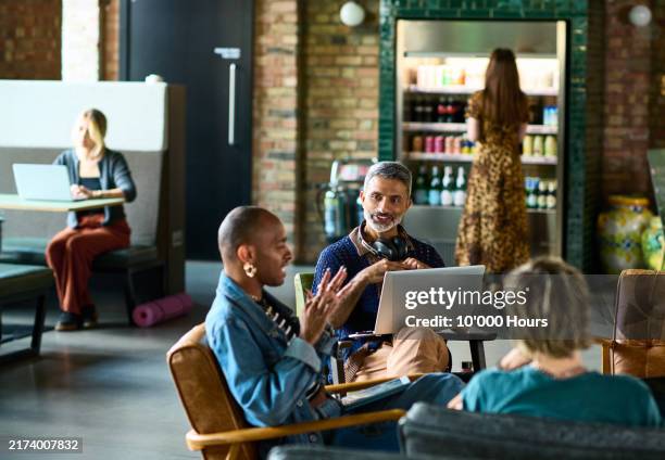 group of business colleagues sitting and discussing in shared office space - coworking stock pictures, royalty-free photos & images