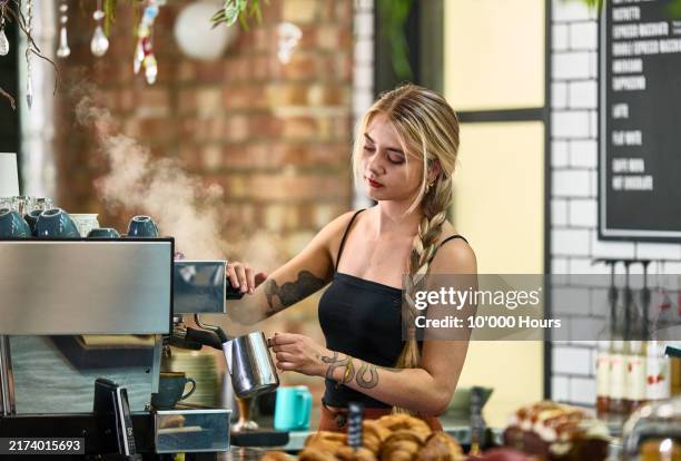 waitress with plaited blonde hair and tattoo, working in cafe, using coffee machine - office temperature stock pictures, royalty-free photos & images