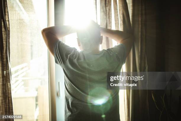 hombre mirando por la ventana - un solo hombre fotografías e imágenes de stock