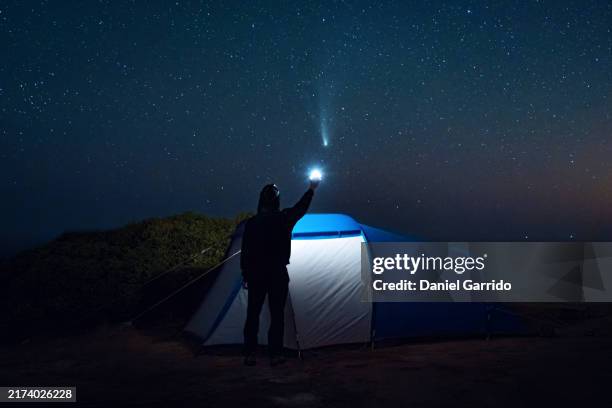 man camping pointing at comet tsuchinshan-atlas (c/2023 a3) in the starry sky. - cometa fotografías e imágenes de stock