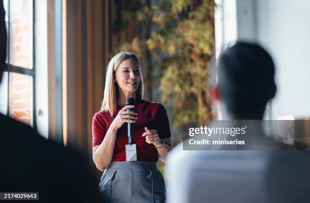 confident speaker presenting to engaged audience at business event - palestrante imagens e fotografias de stock