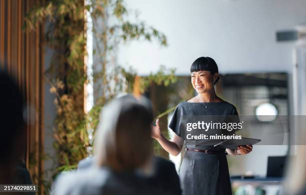 empresaria segura de sí misma que lidera una reunión de equipo con una sonrisa - líder fotografías e imágenes de stock