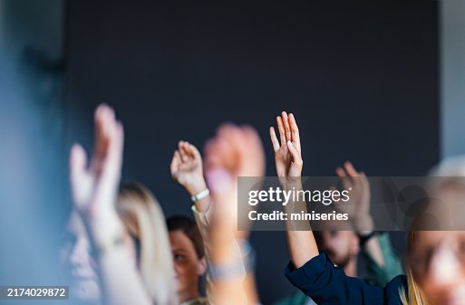 Engaged Audience Raising Hands at Business Event Engaged Audience Raising Hands at Business Event