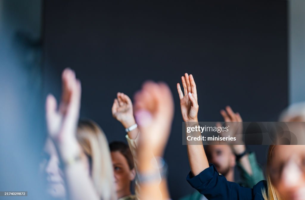 Engaged Audience Raising Hands at Business Event