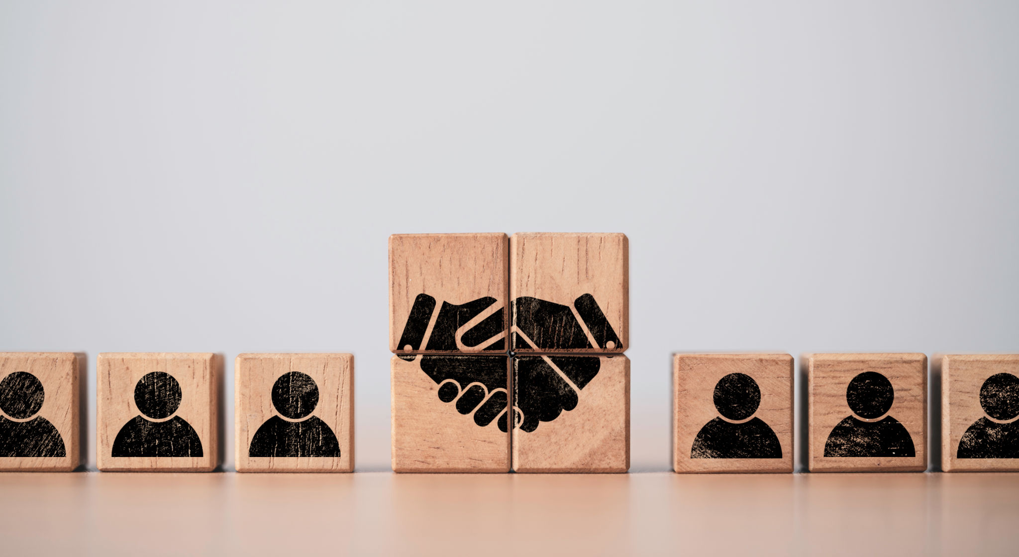 Hand shaking print screen on wooden block cube between human icon for business deal and agreement concept. Hand shaking print screen on wooden block cube between human icon for business deal and agreement concept.