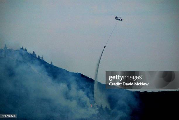 Chinook firefighting helicopter makes a water drop as the Coyote Fire burns more than 11,000 acres of chaparral and forest on July 17, 2003 six miles...