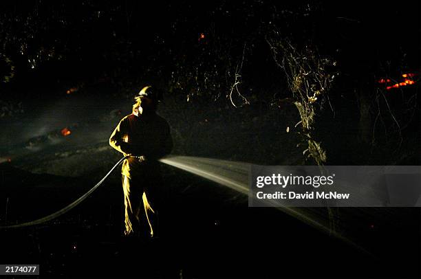 Firefighter hoses down a hot spot in the Lost Valley Boy Scout Camp as the Coyote Fire burns more than 11,000 acres of chaparral and forest on the...