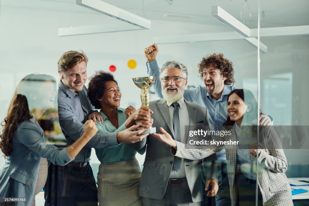 Cheerful business team celebrating winning a trophy in the office.