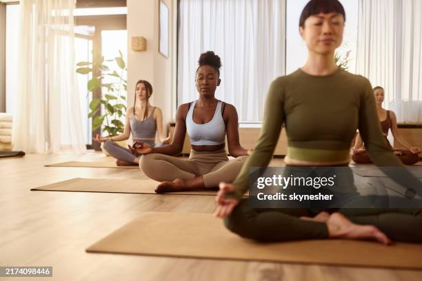athletic women doing meditation exercises at yoga studio. - yoga class stock pictures, royalty-free photos & images