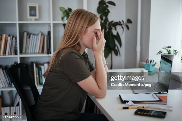 tired woman freelancer rubbing eyes while working on laptop from home, remote worker feeling tired exhausted. eye strain and vision problems - rubbing eyes stock pictures, royalty-free photos & images