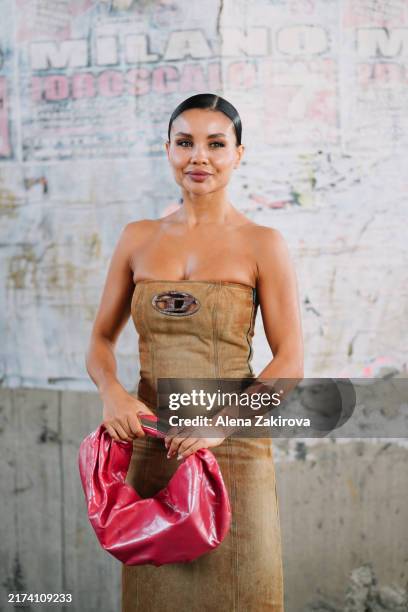 Elena Kruchenska wearing a strapless tan midi dress, gray pointed-toe boots, a pink Diesel handbag is seen outside the Diesel show during the Milan...